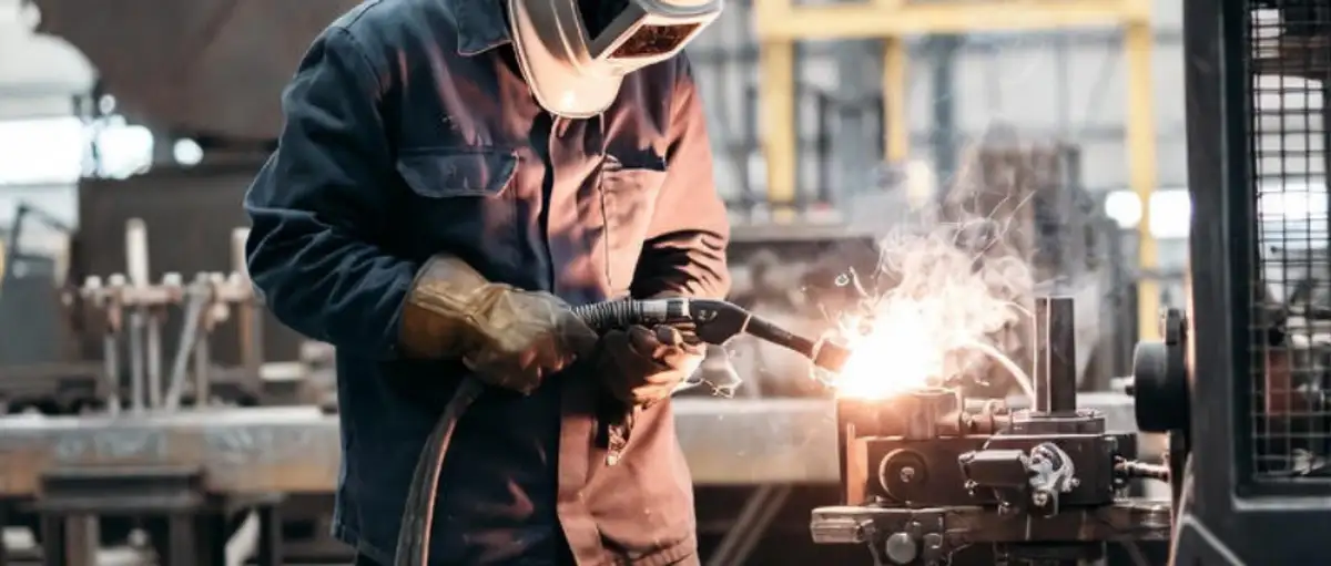 Close-up of a welder in a workshop focusing on a pipe joint, representing public liability and professional indemnity insurance for Australian metalworkers.