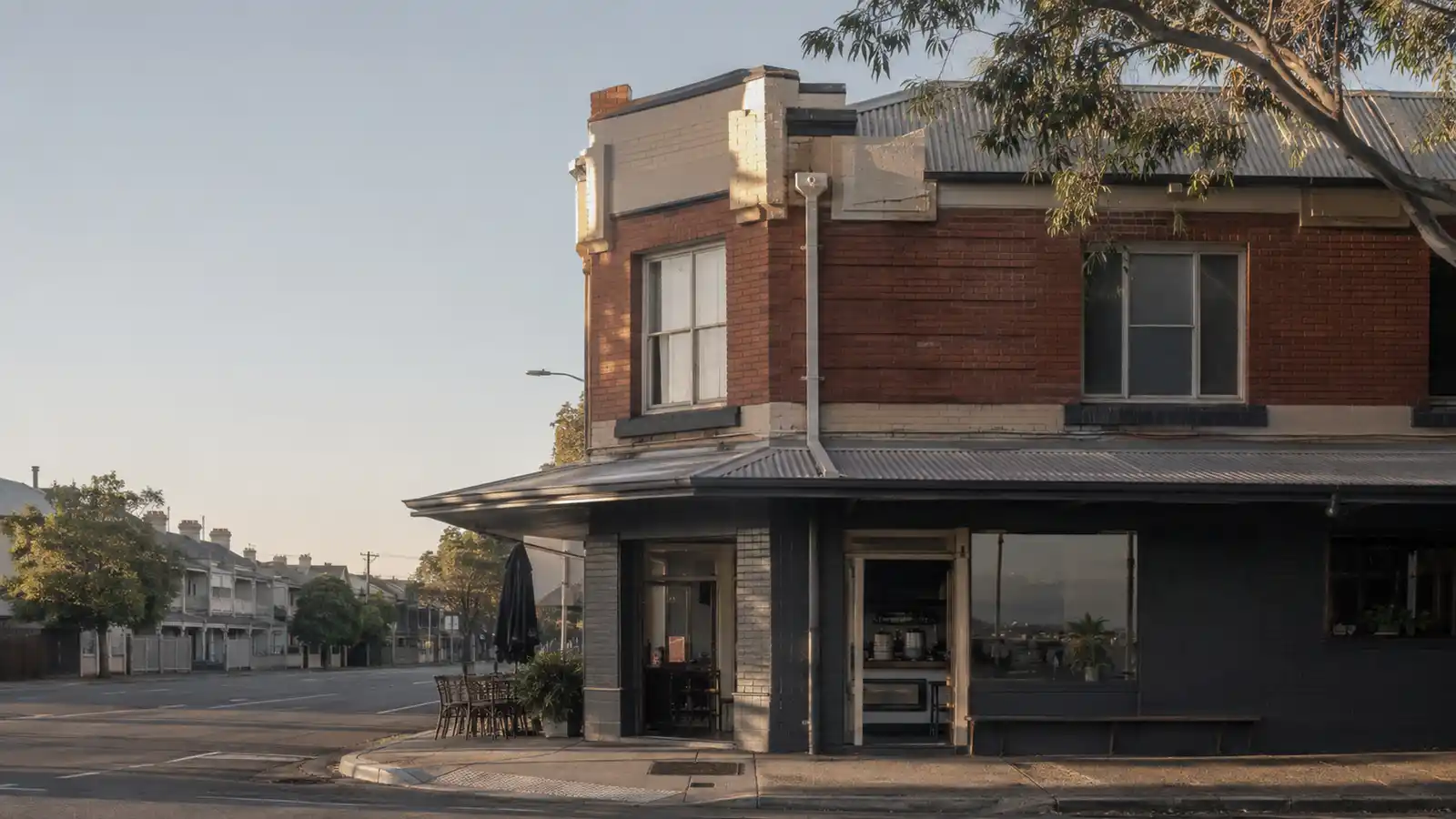 Federation brick corner building with a cafe at street level and two flats above in early morning light