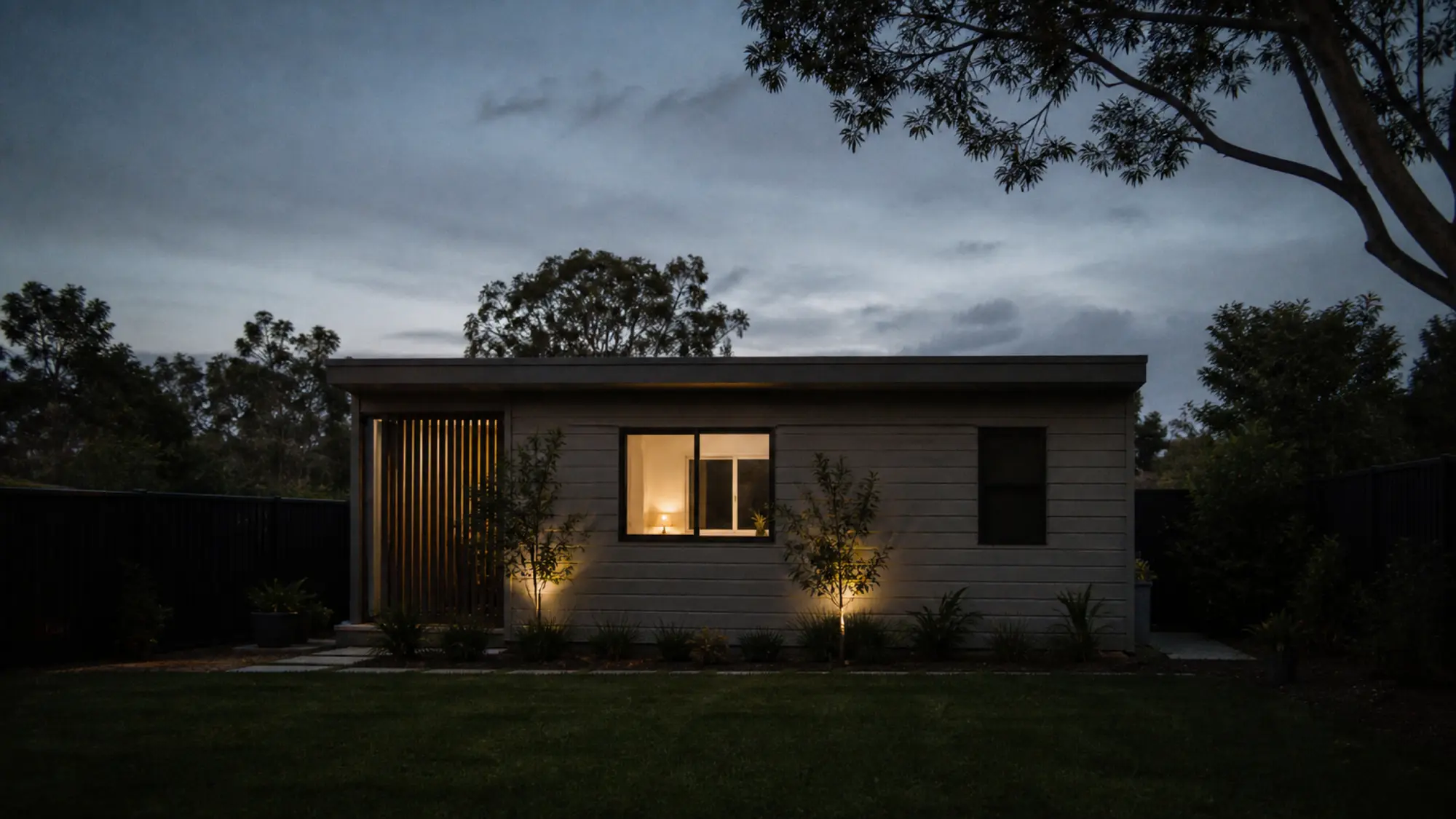 Granny flat exterior at dusk with warm interior lighting for landlord insurance