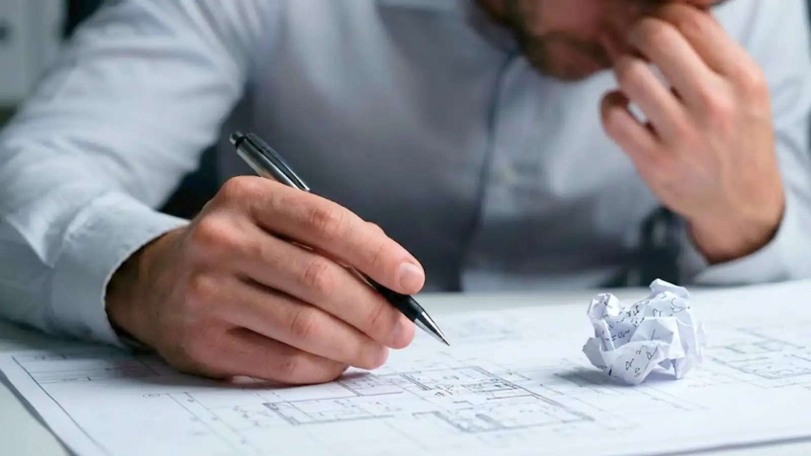 Professional reviewing architectural plans under pressure highlighting the need for errors and omissions insurance