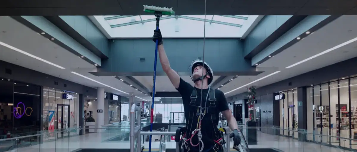 Window cleaner in safety harness cleaning shopping centre skylight – illustrating high-risk commercial cleaning operations requiring specialist public liability insurance