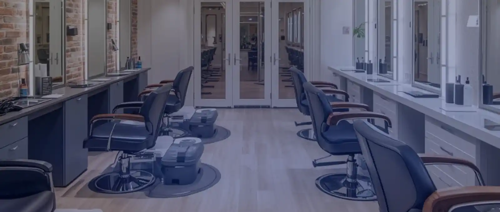 Modern hair salon interior with black leather styling chairs, mirrors, and professional workstations in a contemporary fit-out