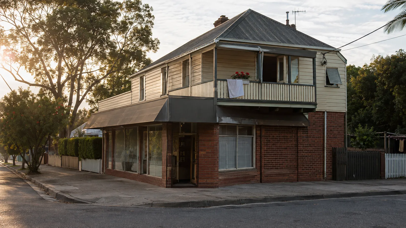 Weathered corner shop-top building with a ground-floor business and family home above in morning light