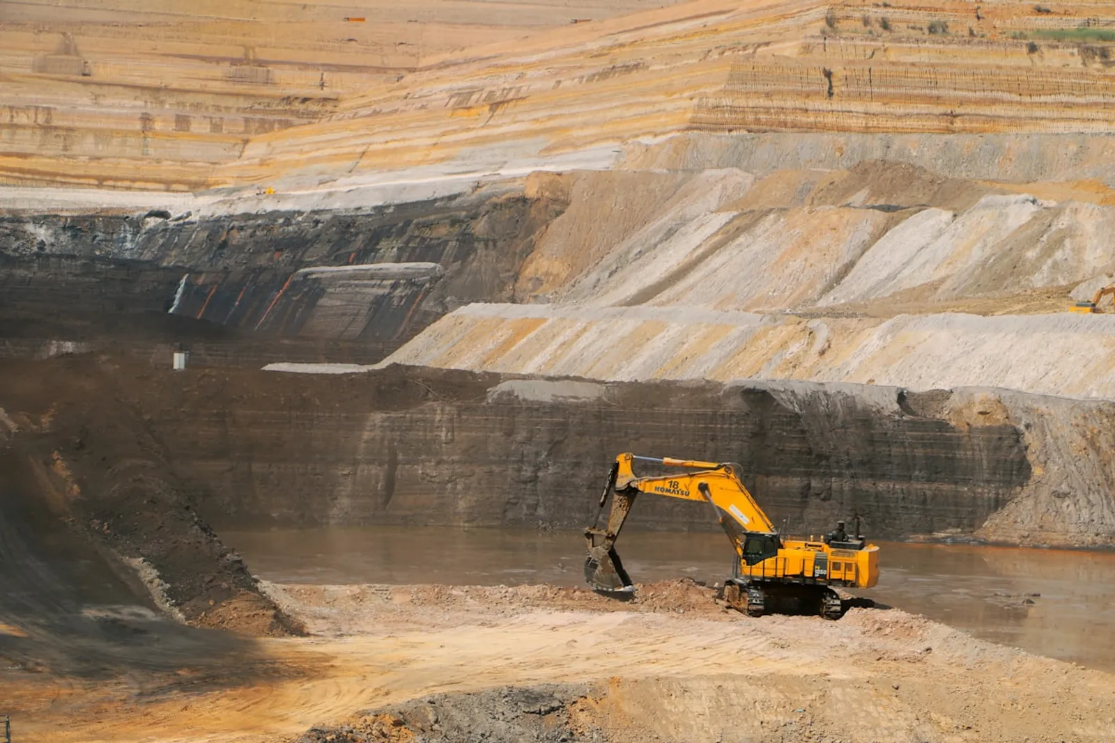 Yellow excavator at open pit mine site
