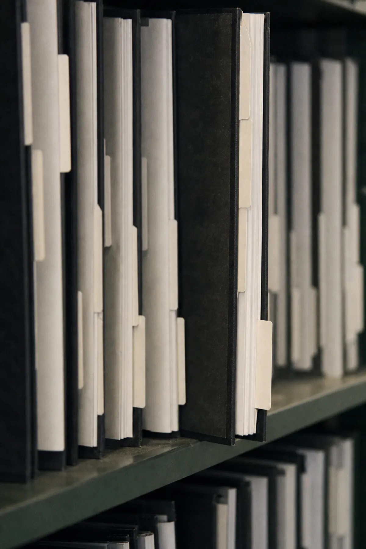 Tabbed specification binders on a shelf, the deliverable specification writer PI cover sits behind