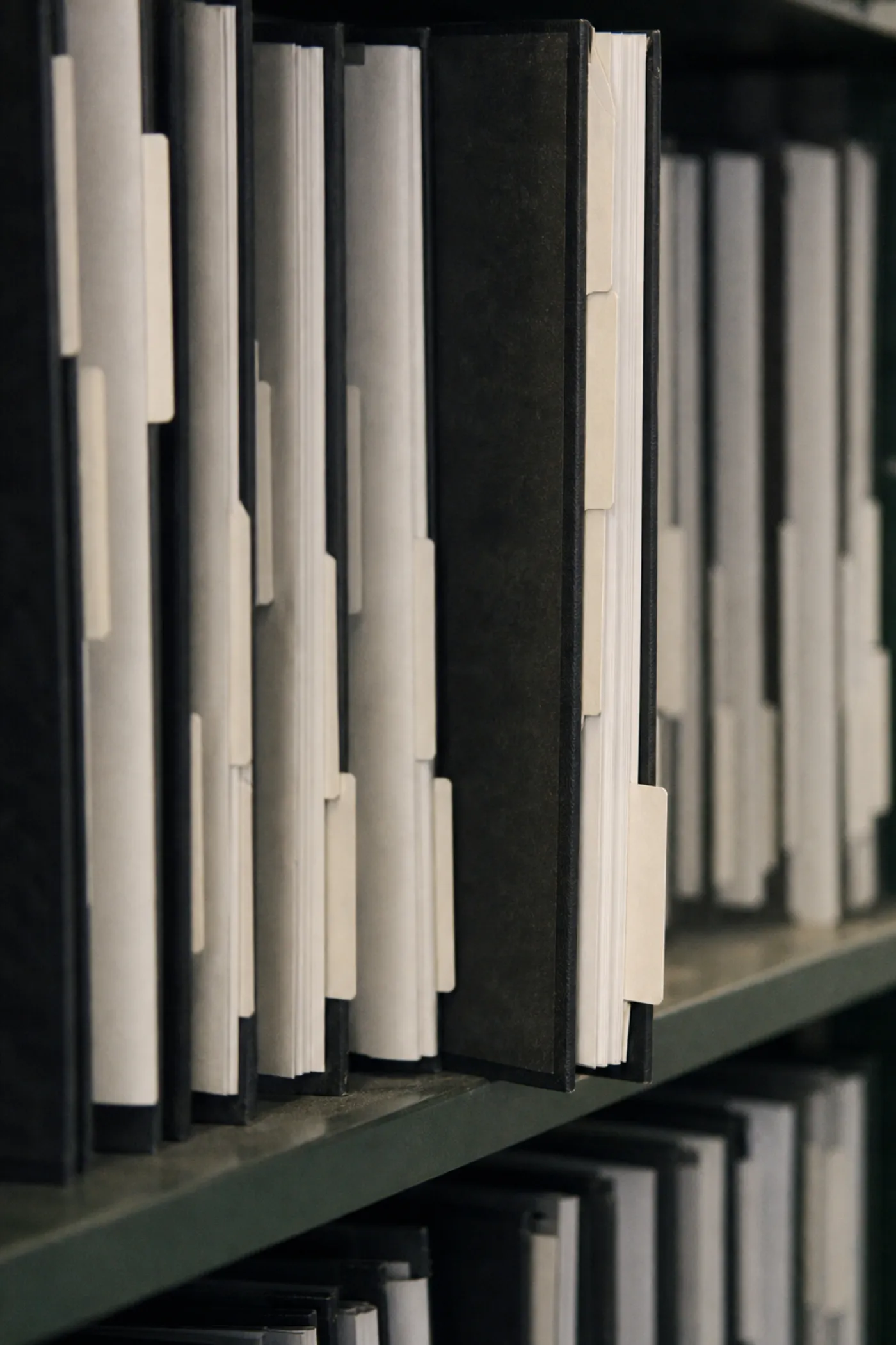 Tabbed specification binders on a shelf, the deliverable specification writer PI cover sits behind