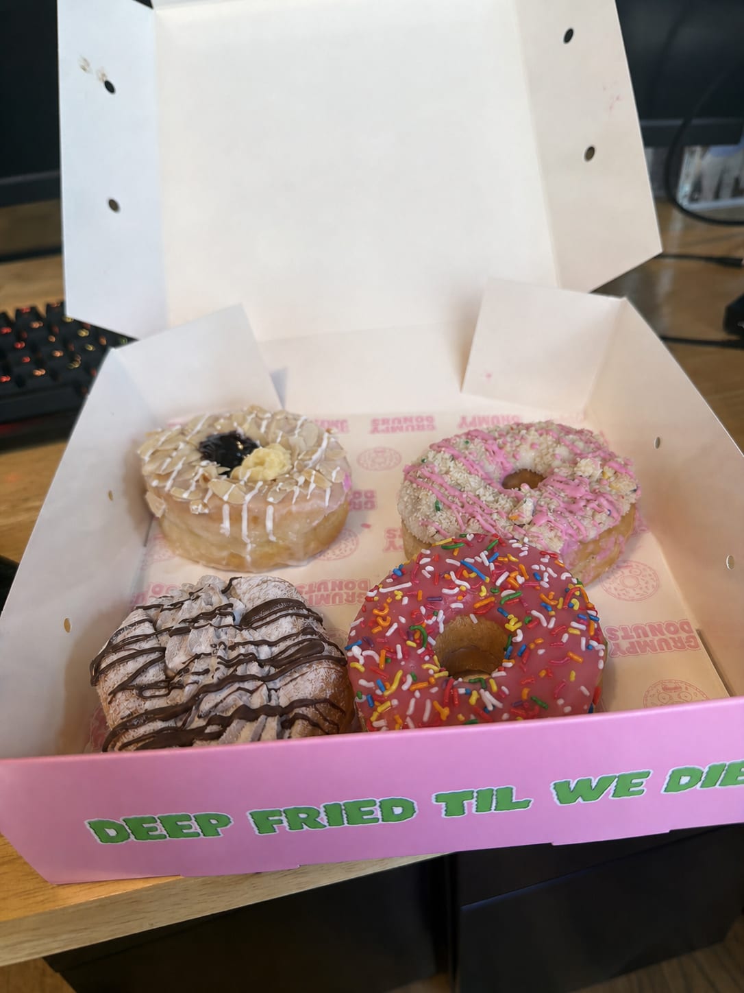 Open Grumpy Donuts box with four donuts on a desk
