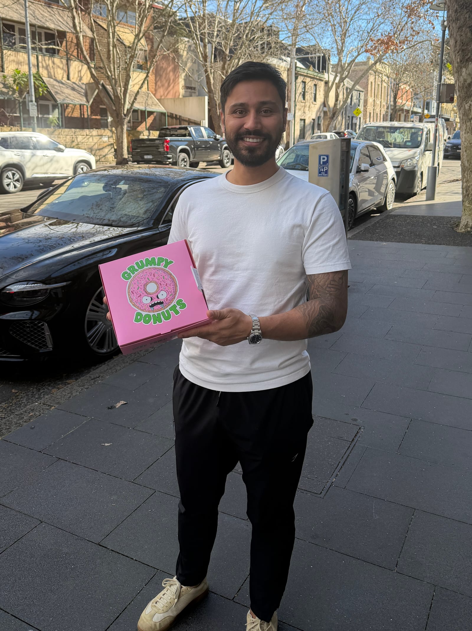 Marel Pencev holding a pink Grumpy Donuts box on a Sydney street